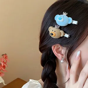 Pair of cute cartoon flocked bear hair clips in blue and brown colors on braided hair