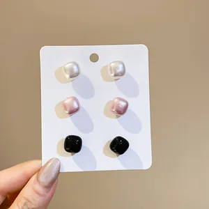 Set of three retro square pearl stud earrings in white, pink, and black colors.