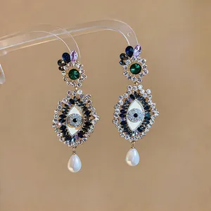 Detailed view of dark-style evil eye earrings with colorful rhinestones and white pearls.