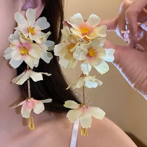 Vue détaillée de grandes boucles d'oreilles à fleurs en tissu avec accents roses.