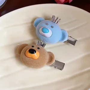 Close-up of adorable flocked bear hair clips with tiny crowns on a ceramic tray