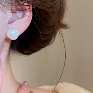 Detailed macro view of an elegant French retro square pearl stud earring worn on an ear