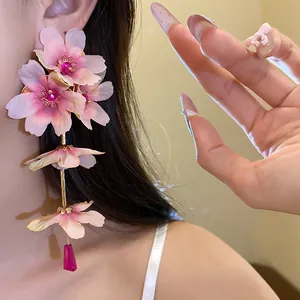 Gros plan détaillé de boucles d'oreilles pendantes en fleurs de tissu rose doux