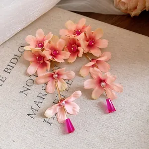 Détail macro de boucles d'oreilles pompons fleurs en tissu avec pétales roses