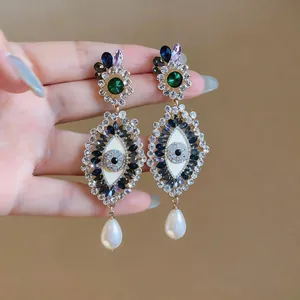 Detail of oversized evil eye earrings with sparkling rhinestones and pearl drops
