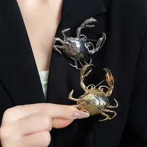 Detail of creative 3D metallic crab brooches in gold and silver on a black blazer