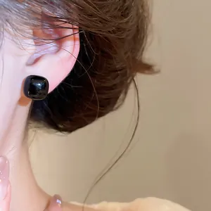 Detailed close-up view of a vintage black square stud earring worn on a model's ear