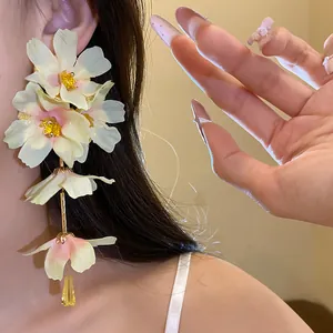 Gros plan de boucles d'oreilles à fleurs en tissu avec cœurs roses et étamines dorées