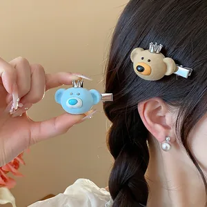 Cute flocked bear hair clips with crown detail shown on hair and held by hand