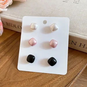Detail view of French retro square pearl stud earrings in white, pink, and black colors