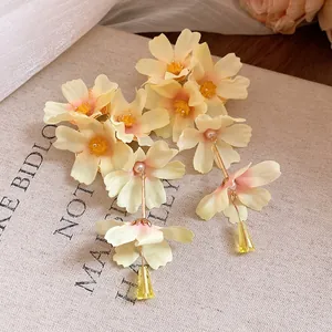 Détail rapproché de boucles d'oreilles fleur en tissu jaune avec longs glands en cristal