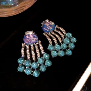 Exquisite detail of vintage oval resin earrings with rhinestone tassels and blue beads.