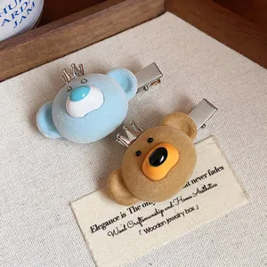 Close-up of cute flocked bear hair clips with crown detail and metal duckbill clip.