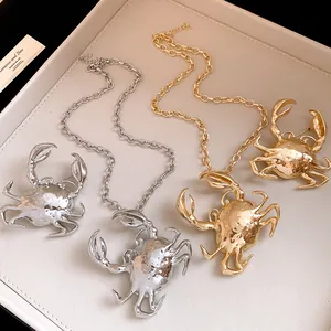Detailed view of metallic gold and silver 3D crab necklaces and brooches on a display tray.
