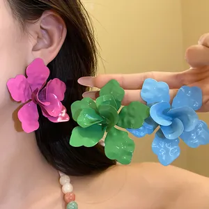 Detalle de pendientes de botón con flores de esmalte en colores rosa verde y azul
