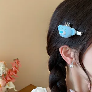 Close-up detail of a cute blue flocked bear hair clip with a mini crown worn by a model