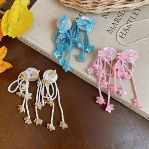 Close-up of colorful flower tassel earrings in pink, blue, and white beaded styles.
