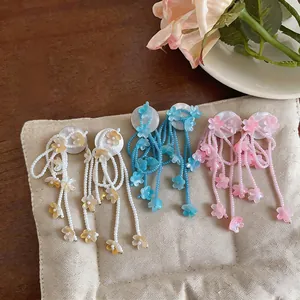 Close-up detail of colorful beaded flower tassel earrings in soft pink, blue and yellow tones