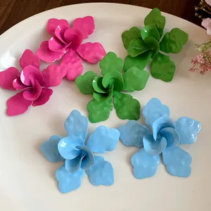 Detalle macro de pendientes de flores de esmalte de colores rosa, verde y azul en un plato