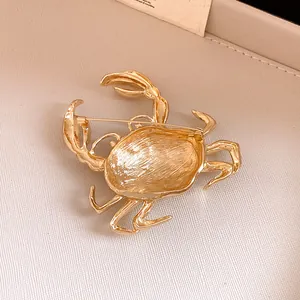 Detail showing the textured gold finish and pin closure of the crab brooch accessory.