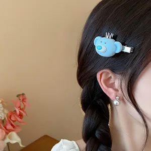 Detailed shot of a cute blue flocked bear hair clip with a silver crown on model's hair