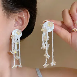 Close-up detail of iridescent flower tassel earrings with elegant white beaded strands.