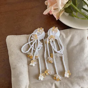 Detailed view of long white beaded tassel earrings featuring dainty yellow flowers