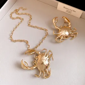 Close-up detail of the creative gold crab pendant necklace and matching brooch jewelry set.
