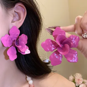 Primer plano de pendientes de flor magenta vibrante con pétalos esmaltados en capas.