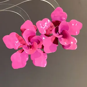 Vista de detalle de pendientes de flores fucsia vibrantes con acabado de esmalte