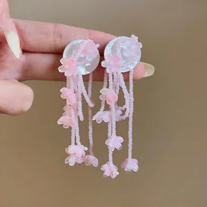 Close-up detail of pink floral tassel earrings with translucent beaded charms.