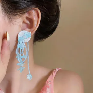 Light blue floral tassel beaded earrings worn by a model in a close-up detail shot