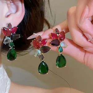 Macro view of luxury multi-color zircon earrings with vibrant green teardrop stones.