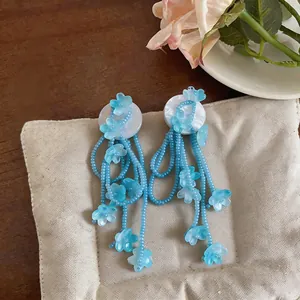 Detail of blue beaded tassel earrings with delicate flower accents on soft cushion