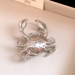 Detailed view of a metallic silver crab brooch with high-shine reflective finish texture