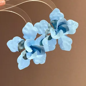 Vista detallada de elegantes pendientes colgantes de flores azul claro con agujas acero
