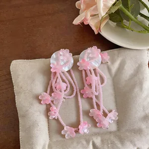 Detailed view of pink flower tassel earrings with intricate beadwork and shell-like studs.