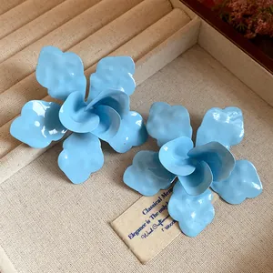 Primer plano del acabado de esmalte azul claro mate de estos pendientes de flores.