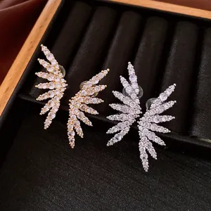 Detailed close-up of gold and silver wing-shaped clip earrings set with sparkling zirconia