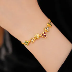 Elegant gold bracelet with colorful zircon flowers worn on a minimalist female wrist.