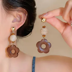 Close-up of retro wooden flower earrings featuring woven bead and gold stud detail
