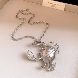 Macro view of oversized 3D crab pendant necklace with polished silver metallic finish