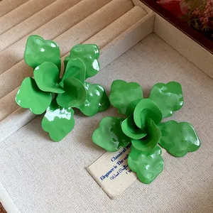 Primer plano de pendientes de flores esmaltadas en verde en un joyero de terciopelo