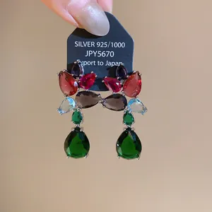 Detailed macro shot of multicolored pear-cut zircon drop earrings on a silver 925 card