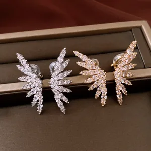 Close-up of elegant gold and silver wing-shaped ear clips with sparkling cubic zirconia