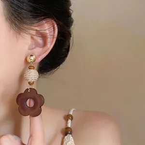 Detailed view of a retro ethnic style wooden flower dangling earring worn by an Asian model