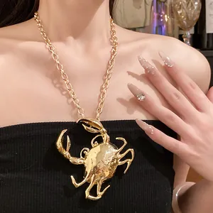 Detail shot of a large 3D golden crab pendant necklace with chunky chain on model