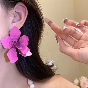 Primer plano de pendientes de botón con flor de esmalte rosa intenso en una oreja