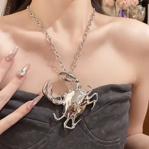 Detailed macro view of a bold stereoscopic silver crab pendant necklace worn by a model.
