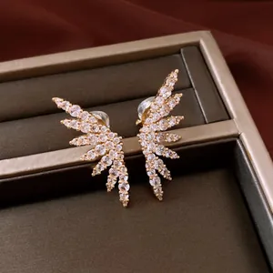 Macro detail view of sparkling gold-plated wing clip-on earrings with cubic zirconia